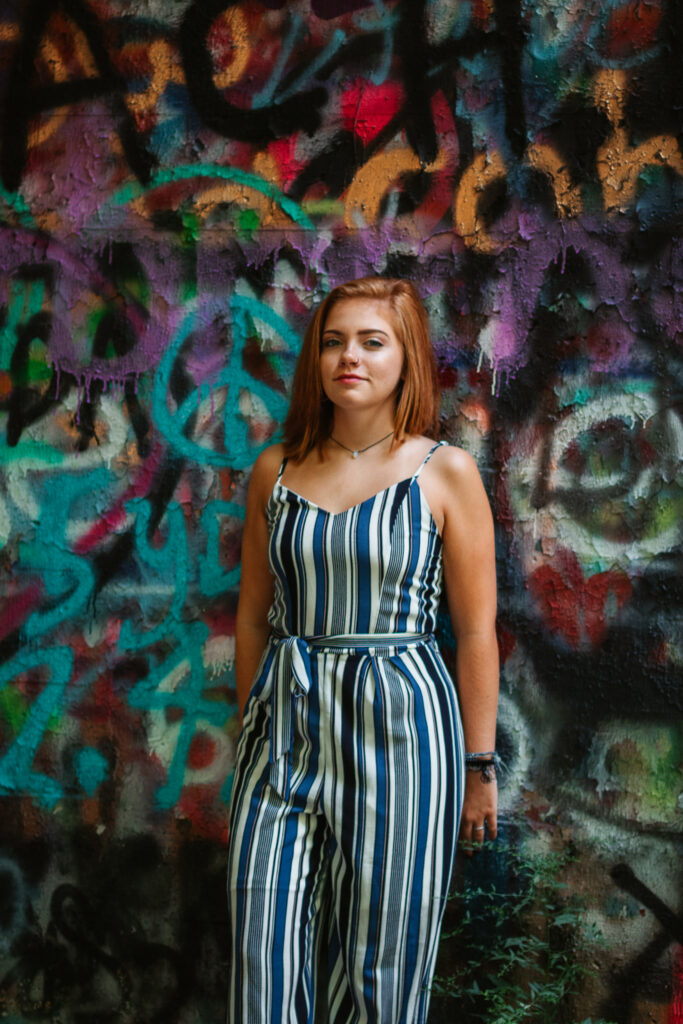 Woman in jumpsuit standing in front of graffiti wall
